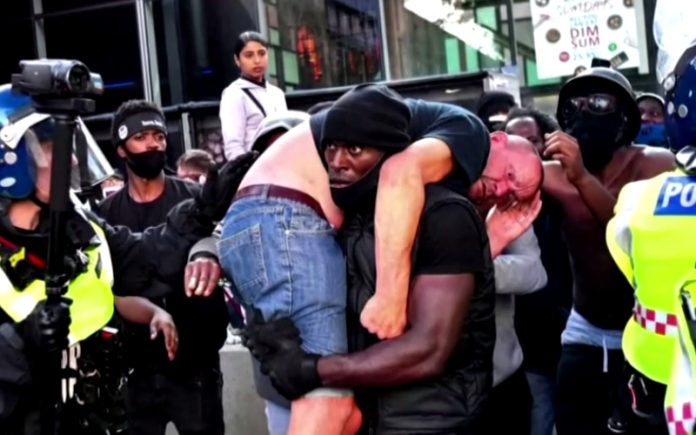 Manifestante britânico carrega homem nas costas para impedir que fosse seriamente ferido