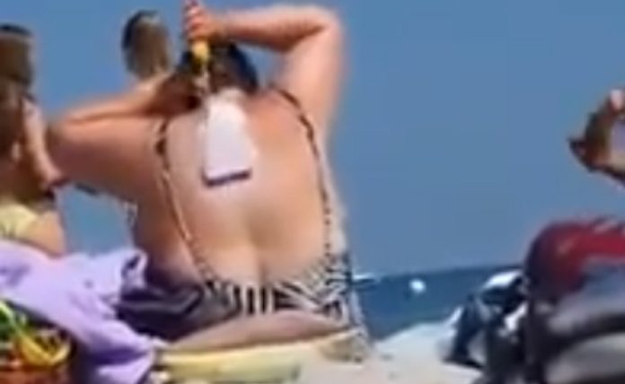 Mulher leva rolo para a praia para espalhar protetor nas costas