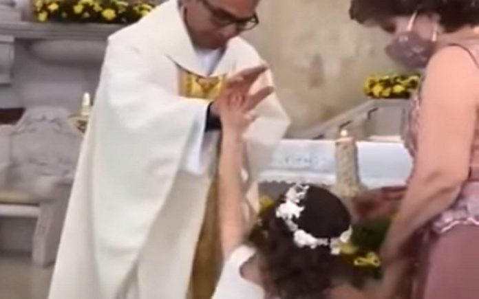 Menina dá um hi5 a padre quando ele lhe estava a dar a bênção Menina dá um hi5 a padre quando ele lhe estava a dar a bênção