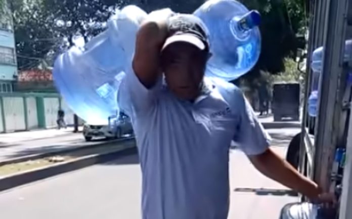 Homem carrega sozinho 5 garrafões de 20 litros de água Homem carrega sozinho 5 garrafões de 20 litros de água