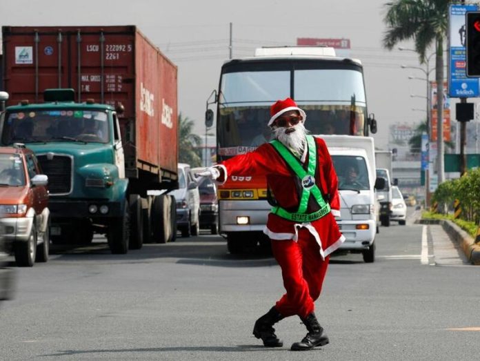 Pai Natal dança no transito das Filipinas Imagemde transito com caminhão e onibus, na frente um papai noel comanda o tráfego