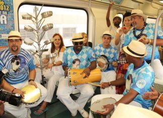 Músicos com camisa de escola de samba da Portela tocam instrumentos musicais no trem