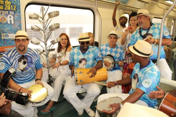 Músicos com camisa de escola de samba da Portela tocam instrumentos musicais no trem