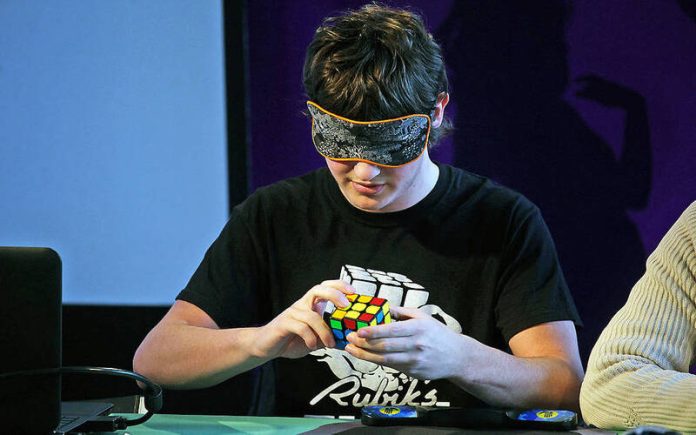 A habilidade de um jovem de resolver os cubos de Rubik enquanto faz malabarismo