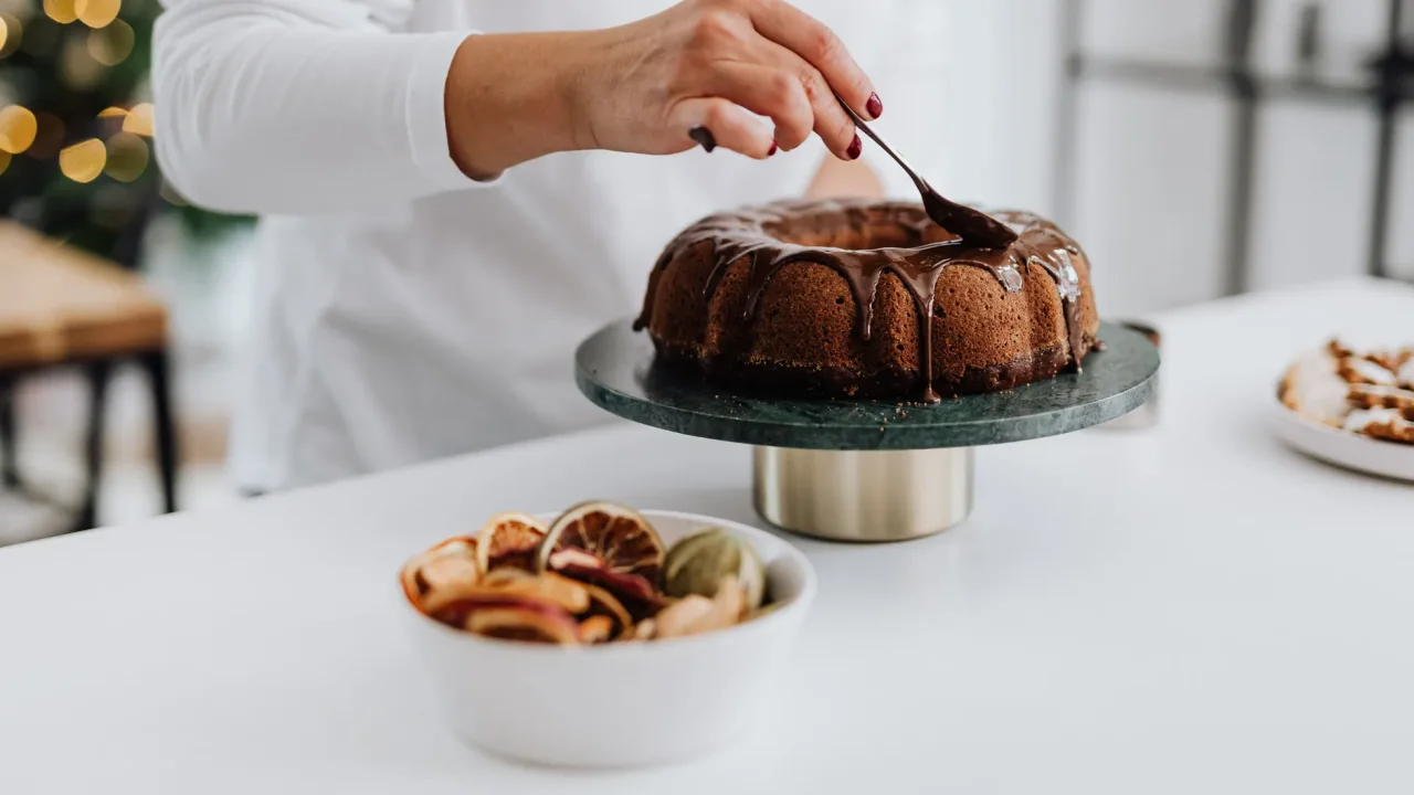 Illustrative photograph. It does not confirm the identity of any person mentioned in the article. A person decorates a chocolate bundt cake with icing in a stylish kitchen setting.